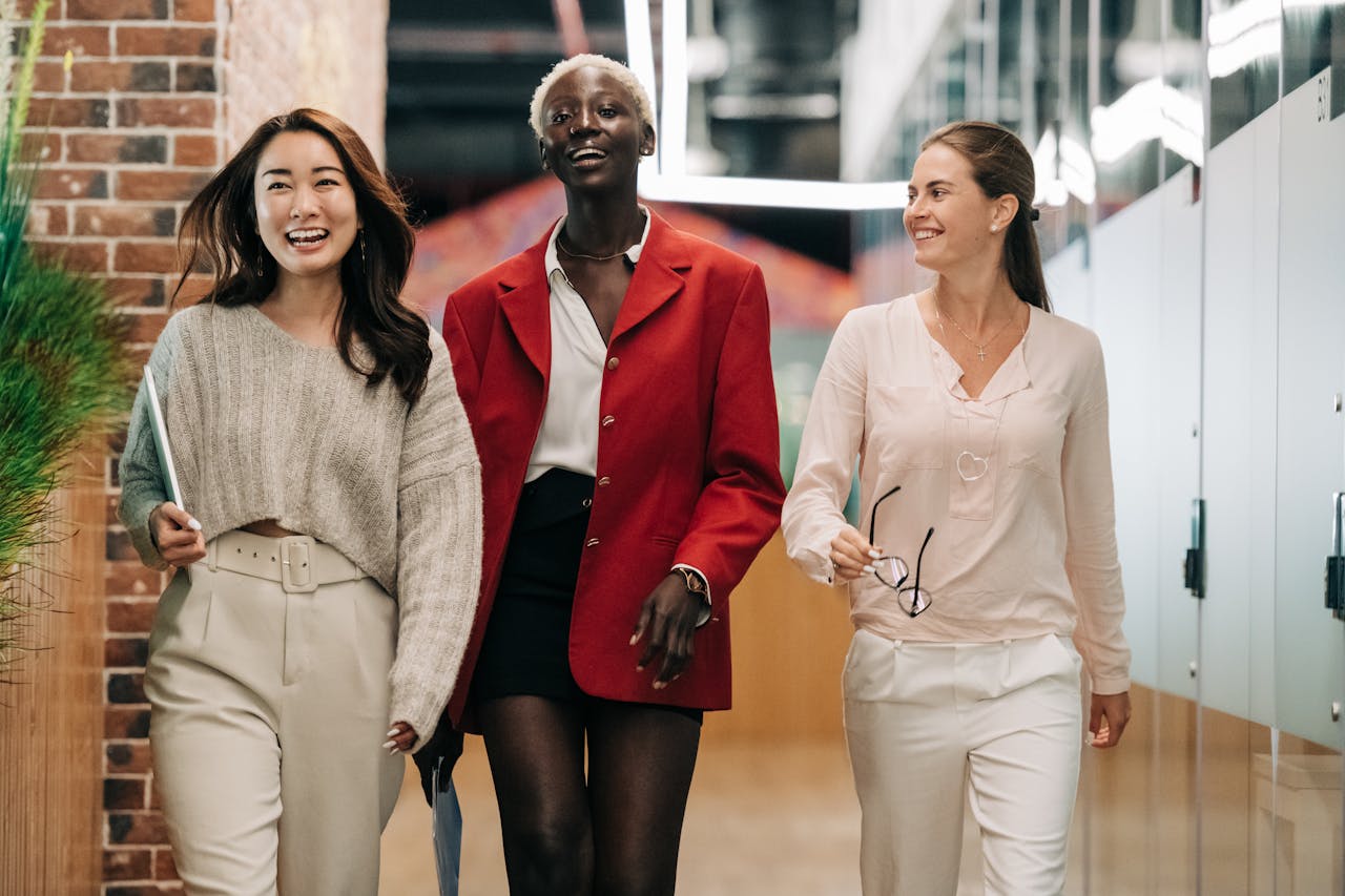 The Art of Drawing Readers In: Your attractive post title goes here Three diverse and confident businesswomen walking together in a modern office hallway, exuding professionalism and joy.